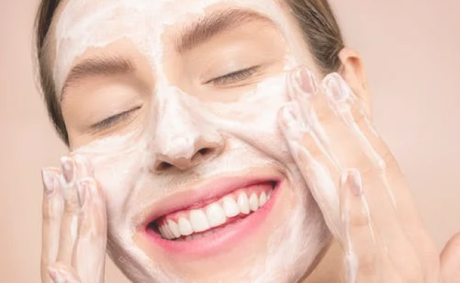 Mujer echándose crema por toda la cara